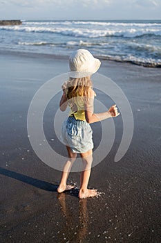 Young girl jumping and running waves at beach on sunset time.