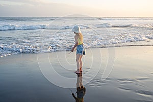 Young girl jumping and running waves at beach on sunset time.