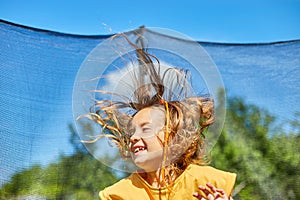 A young girl jumping up and down on her trampoline outdoors