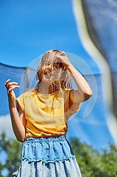 A young girl jumping up and down on her trampoline outdoors