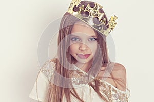 Young girl kid with a cute smile wearing a crown and a white sequined dress on Holiday birthday party isolated on white background