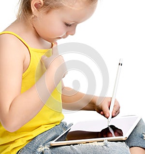 Young girl kid sitting reading learning drawing on digital tablet touch screen pad with pencil