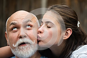 Young girl kissing grandfather, close up. Old and young Couple in love kissing. Romantic moment. Dreamy kiss.