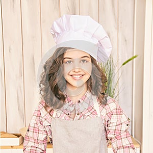 Young girl at kitchen. Little cook chef. Cute female portrait. Baker smile