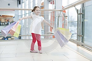 Young girl laden with paper shopping bags