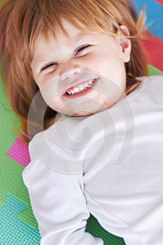 Young girl, laughing and happiness portrait of a baby on a home playpen ground with a smile. Ginger infant, kid laugh