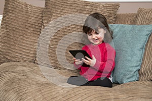 Young girl laughs at tablet