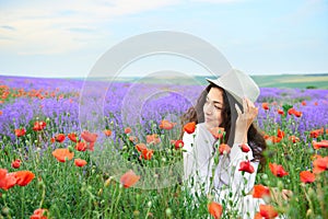 Young girl is in the lavender field with red poppy flowers, beautiful summer landscape