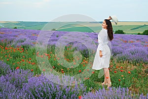 Young girl is in the lavender field with red poppy flowers, beautiful summer landscape