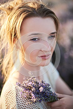 Young girl in the lavender fields with bouquet of flowers