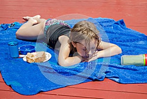 Young girl laying out in the sun on a blue blanket