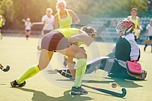 Young girl lead the ball into net in hockey match