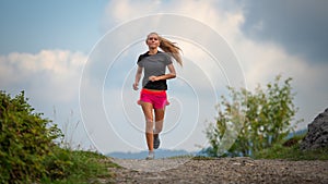 Young girl with lean physique running on hill dirt