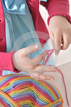 Young girl learning to crochet with multicoloured wool yarn. Homemade handiwork can be a nice and creative present