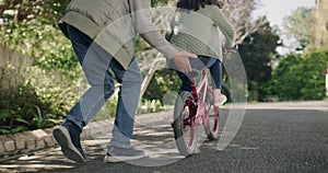 Young girl learning to ride a bicycle in the neighborhood. Loving, caring and proud grandparent helping grandchild to