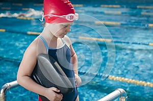 Young girl learning to swim in the pool with foam board