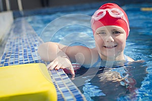 Young girl learning to swim in the pool with foam board