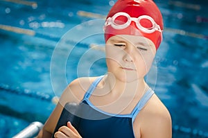 Young girl learning to swim in the pool with foam board