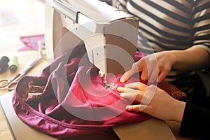 A young girl learns from her mother how to repair her clothes with a vintage sewing machine at home