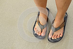 Young girl legs in flipflop sandals on sea beach