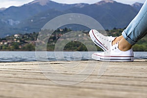 Young girl legs on a pier with blue jeans and white shoes