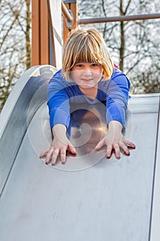 Young girl lies forward on slide