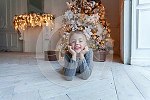 Young girl lies near a Christmas tree