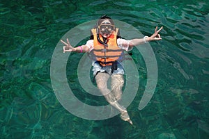 Young girl in life jacket suit and snorkel floating on sea surface