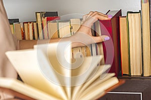 Young girl in a light dress is reading a book. Female hands hold a book in their hands