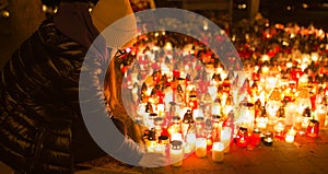 A young girl lights a candle on a religious of all saints day