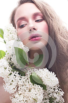 A young girl with lilac and bright creative make-up. Beautiful model with flowers and long hair. White isolated background. Pure s