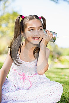 Young girl listening through tin can phone