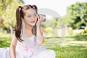 Young girl listening through tin can phone