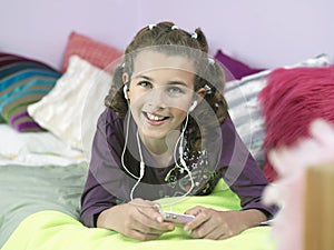 Young Girl Listening To MP3 Player In Bed