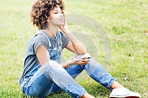 Young girl listening to music in park, relaxing.