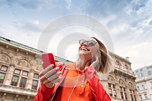 Young girl listens to music with headphones in front of Vienna State Opera, Austria