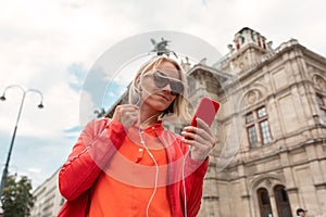 Young girl listens to music with headphones in front of Vienna State Opera, Austria