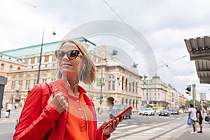 Young girl listens to music with headphones in front of Vienna State Opera, Austria