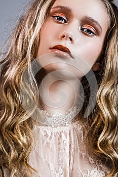 Young girl with long blond hair and  plant in hand  grey background