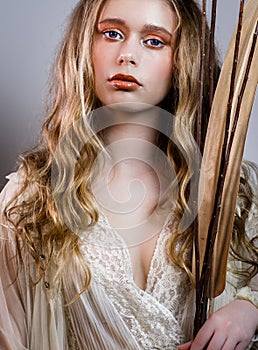 Young girl with long blond hair and  plant in hand  grey background