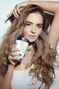 Young girl with long curly hair and cup of coffee in h