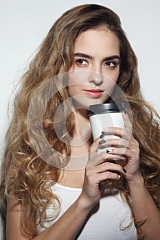 Young girl with long curly hair and cup of coffee in h