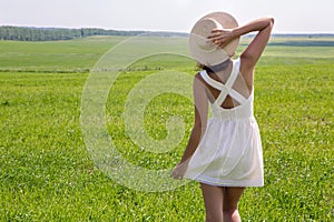 Young girl with long dark hair standing on a green field