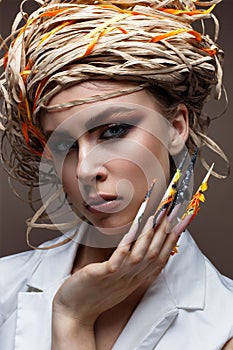 A young girl with long decorated nails and bright creative makeup. Beautiful model with a straw hat on her head. Beautiful manicur