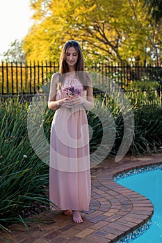 A young girl in a long dress stands near the pool