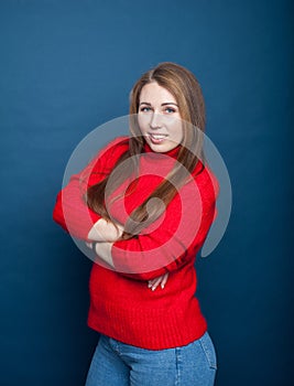 Young girl with long hair on  blue background in  red knitted sweater