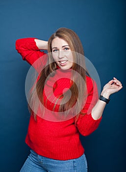 Young girl with long hair on  blue background in  red knitted sweater