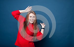 Young girl with long hair on  blue background in  red knitted sweater