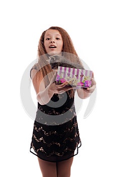 Young girl with long hair in a festive black dress with a gray kitten in a gift box in his hands