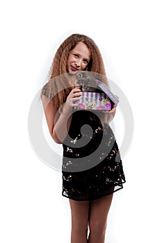 Young girl with long hair in a festive black dress with a gray kitten in a gift box in his hands